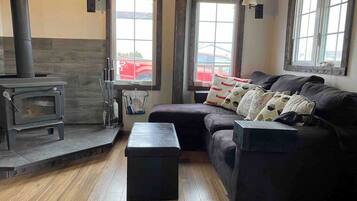 A cozy living room with a wood-burning stove, a sofa, and a small table.