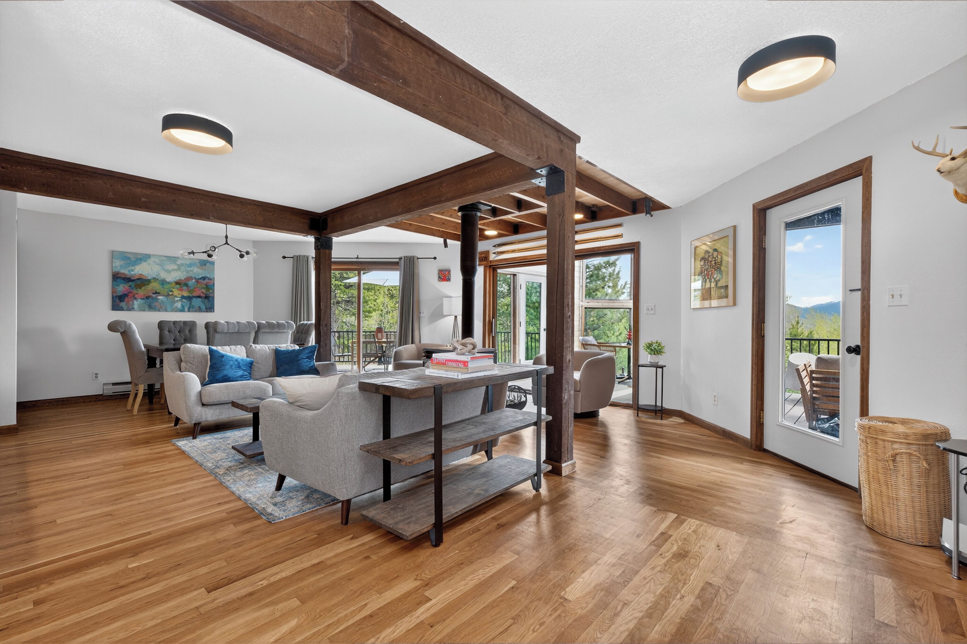 A spacious living area with a wooden floor, a gray sofa, a coffee table, and a bookshelf.