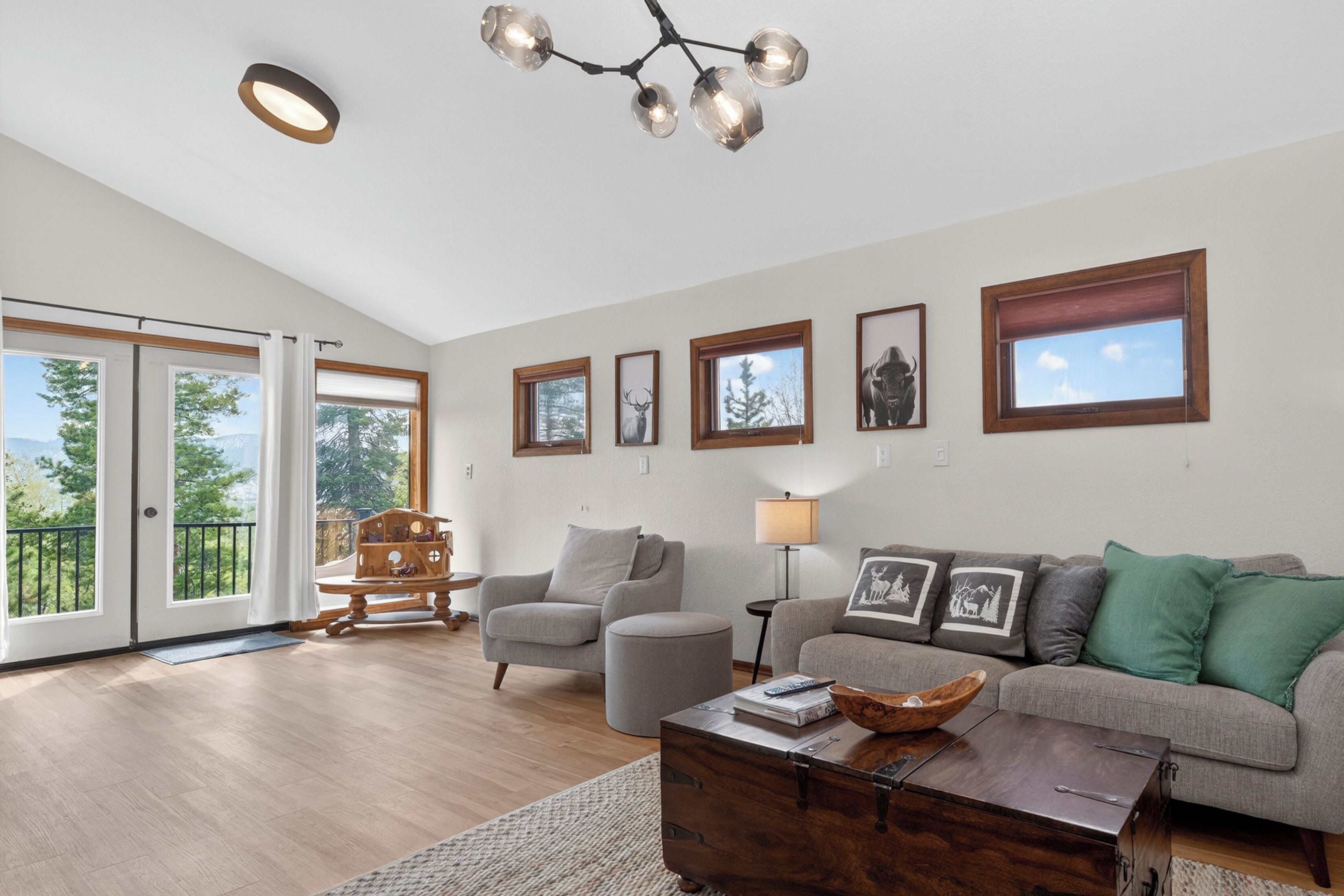 A spacious living room with a sofa, armchair, and coffee table, a wooden chest, and a chandelier.