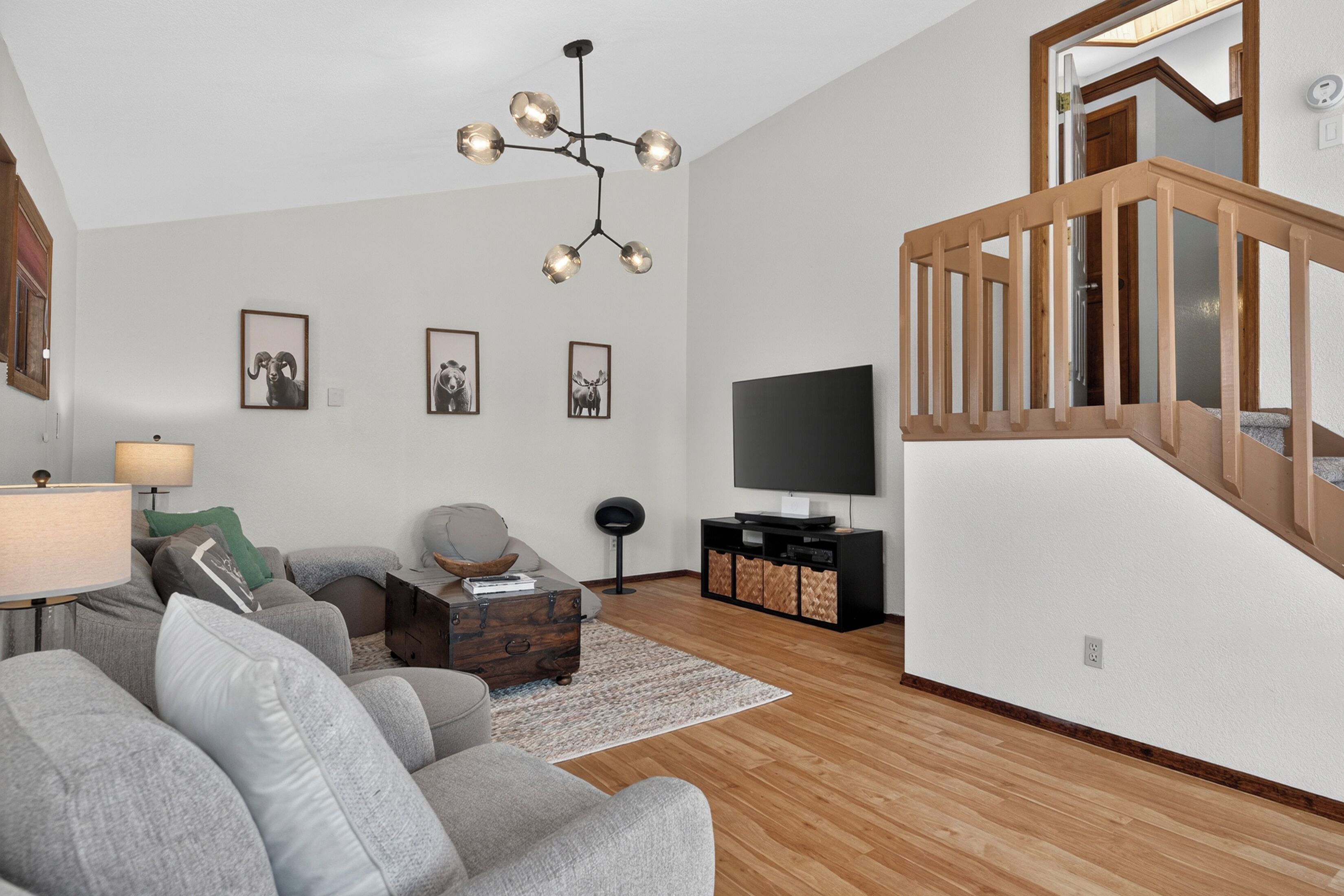 A modern living room with a sofa, a coffee table, a TV stand, and a staircase.