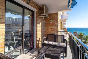 A balcony with wicker furniture, a glass door, and a view of the sea. - Apartment in Nerja Near Carabeillo Beach (Nerja)