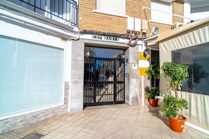 A building entrance with a metal gate, a sign reading 'EDF BAHIA', and potted plants on the ground. - Apartment in Nerja Near Carabeillo Beach (Nerja)