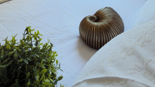 Een slaapkamer met een bed, een raam met gordijnen, een kamerplant en een houten garderobe.