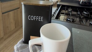 Een keuken met een koffiezetapparaat, een witte mok en een fornuis.