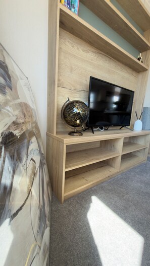 Un meuble de rangement en bois abritant un téléviseur à écran plat, un globe terrestre et un vase blanc.