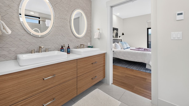 Ein modernes Badezimmer mit zwei Waschbecken, einem Holzkonsolentisch und zwei Spiegeln an der Wand.