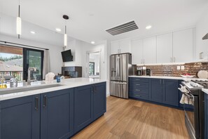 A modern kitchen with dark blue cabinets, stainless steel appliances, and a large island. - Timber Fox Building C Unit 3308 Downtown 3 bedroom, A/C, Private deck with views (Winter Park)