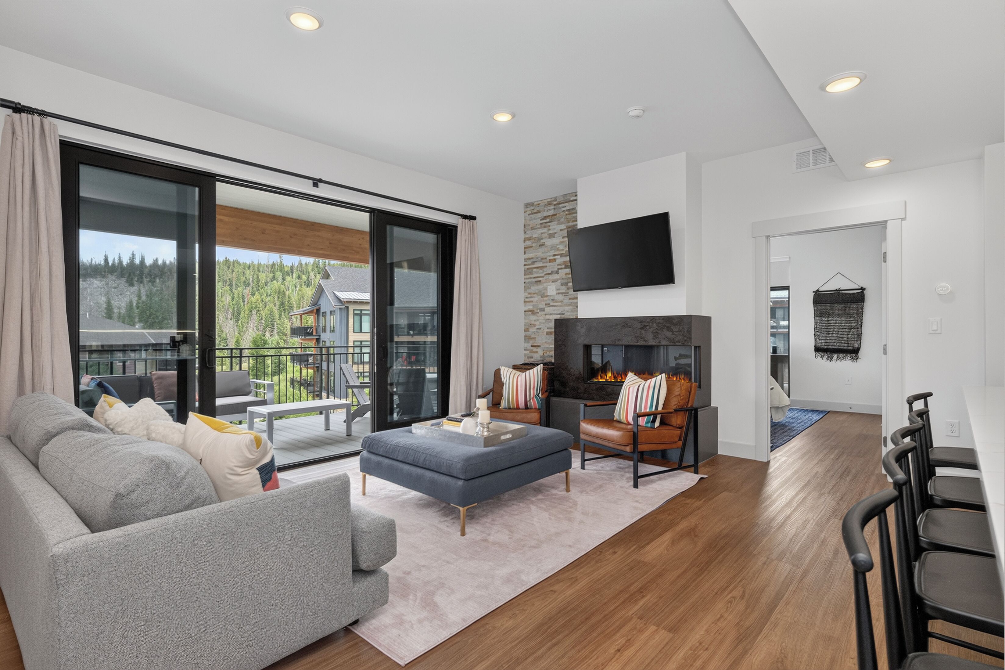 A modern living room with a sofa, ottoman, and a fireplace.