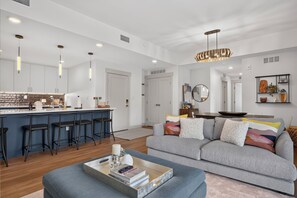 A modern kitchen with bar stools, a dining area with a sofa, and a living room with a coffee table. - Timber Fox Building C Unit 3308 Downtown 3 bedroom, A/C, Private deck with views (Winter Park)