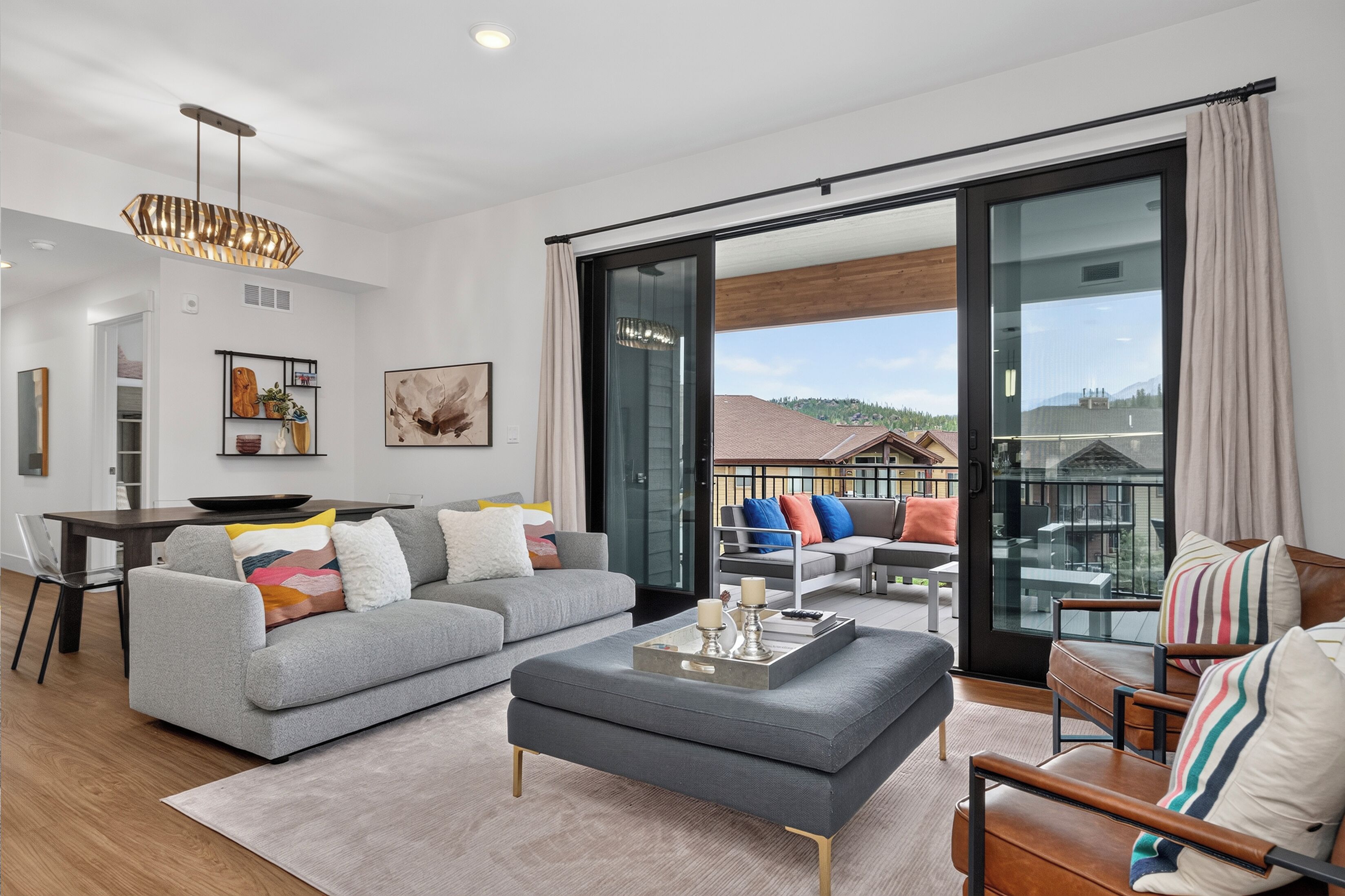 A modern living room with a grey sofa, a coffee table, and a balcony with outdoor furniture.