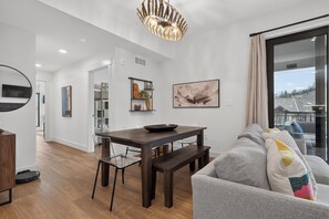 A modern living room with a dining area, a grey sofa, and a large window with a view. - Timber Fox Building C Unit 3308 Downtown 3 bedroom, A/C, Private deck with views (Winter Park)