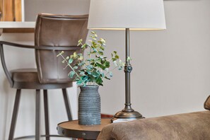 Ein runder Tisch mit einer Lampe und einer Pflanzvase mit Grünpflanzen.