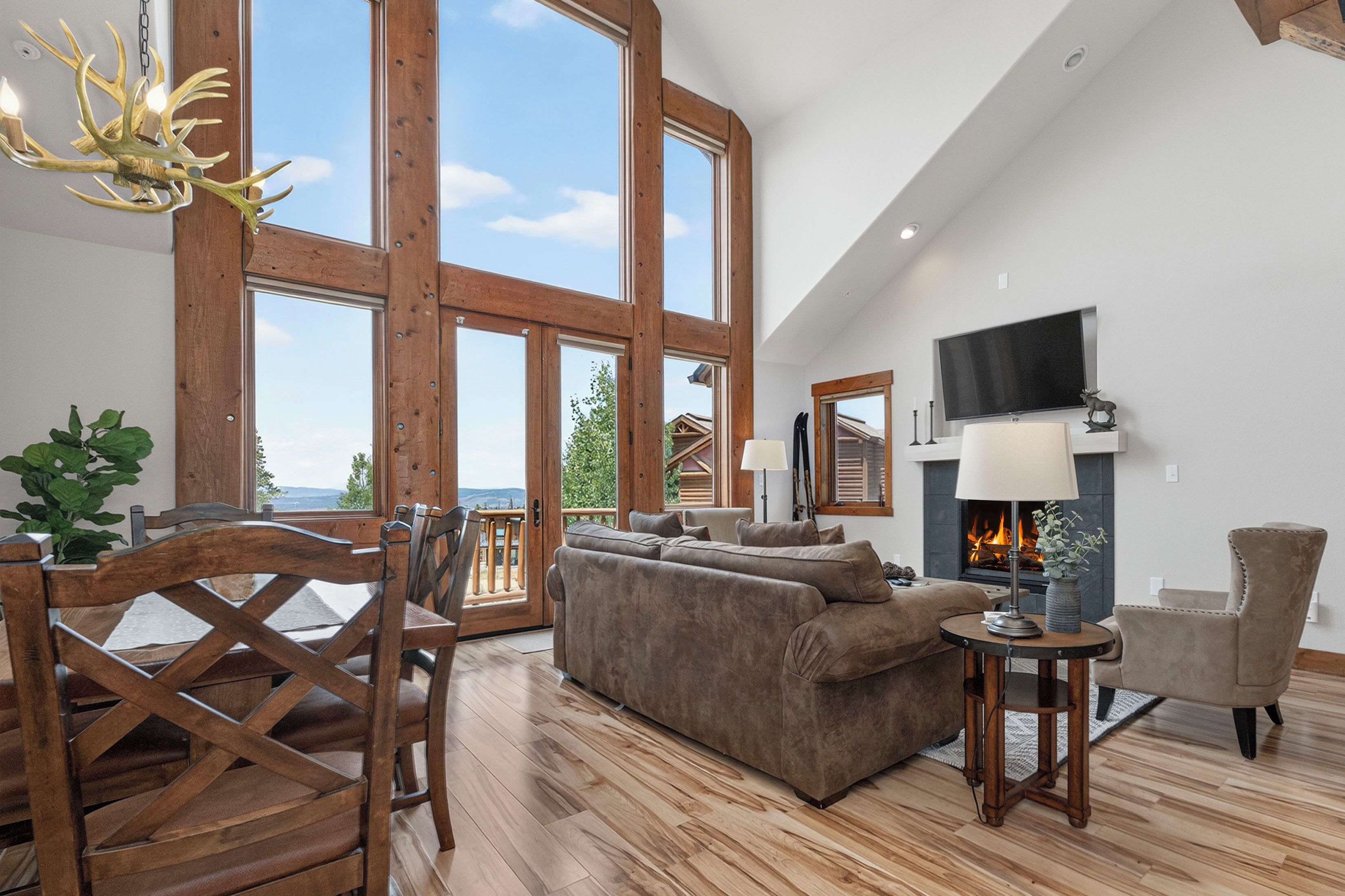 A spacious living room with a fireplace, a television, and a large window overlooking a scenic landscape.