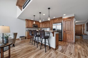 Eine moderne Küche mit Holzschränken, einem Edelstahlkühlschrank und einer Bar mit Hockern.