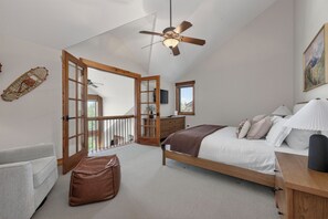 Ein Schlafzimmer mit Bett, Deckenventilator, Fenster und einer Tür, die auf einen Balkon führt.