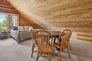 A cozy attic bedroom with a wooden sloped ceiling, a bed with pillows, a small table, and chairs. - 604 GCR 8304 Cabin in the woods, private HT mt views in a secluded neighborhood (Tabernash)