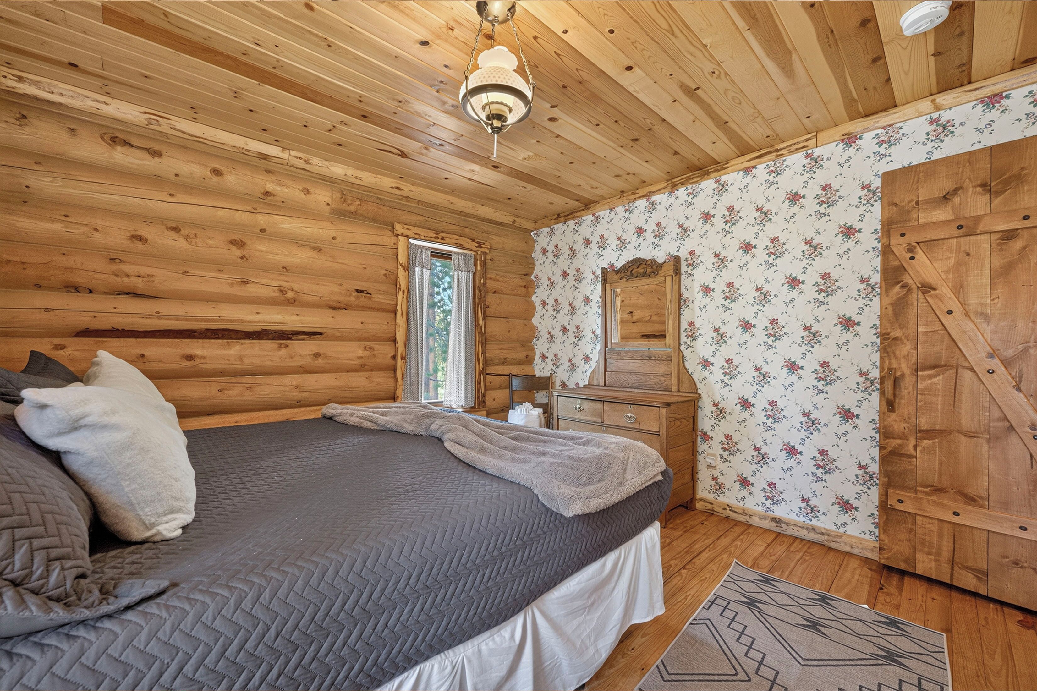 Une chambre dans une cabane en bois, avec un lit, une commode et un miroir.