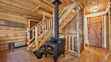 Interior de madera con chimenea, escaleras de madera y una puerta.