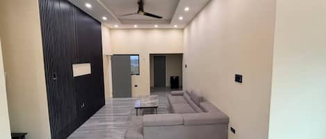 A modern living room with a sectional sofa, a small table, and a ceiling fan.