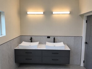 Ein Badezimmer mit zwei Waschbecken, einem Spiegel und einer Leuchte darüber.