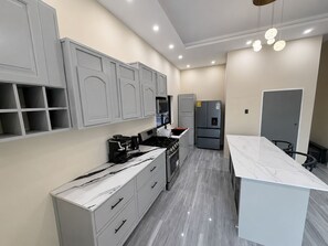 A modern kitchen with white cabinetry, a marble countertop, and a built-in oven. -     Relax in Style  Modern Apartment with Balcony Overlooking the Pool (Hellshire)