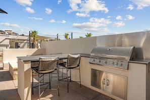 An outdoor kitchen with a stainless steel grill, two chairs, and a table. - Paradise Palace: Lagoon Front! Pool + Waterslide (St. George)