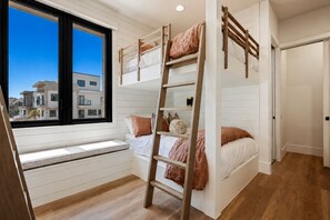Ein Schlafraum mit Etagenbett, Fenster und Blick auf Gebäude.