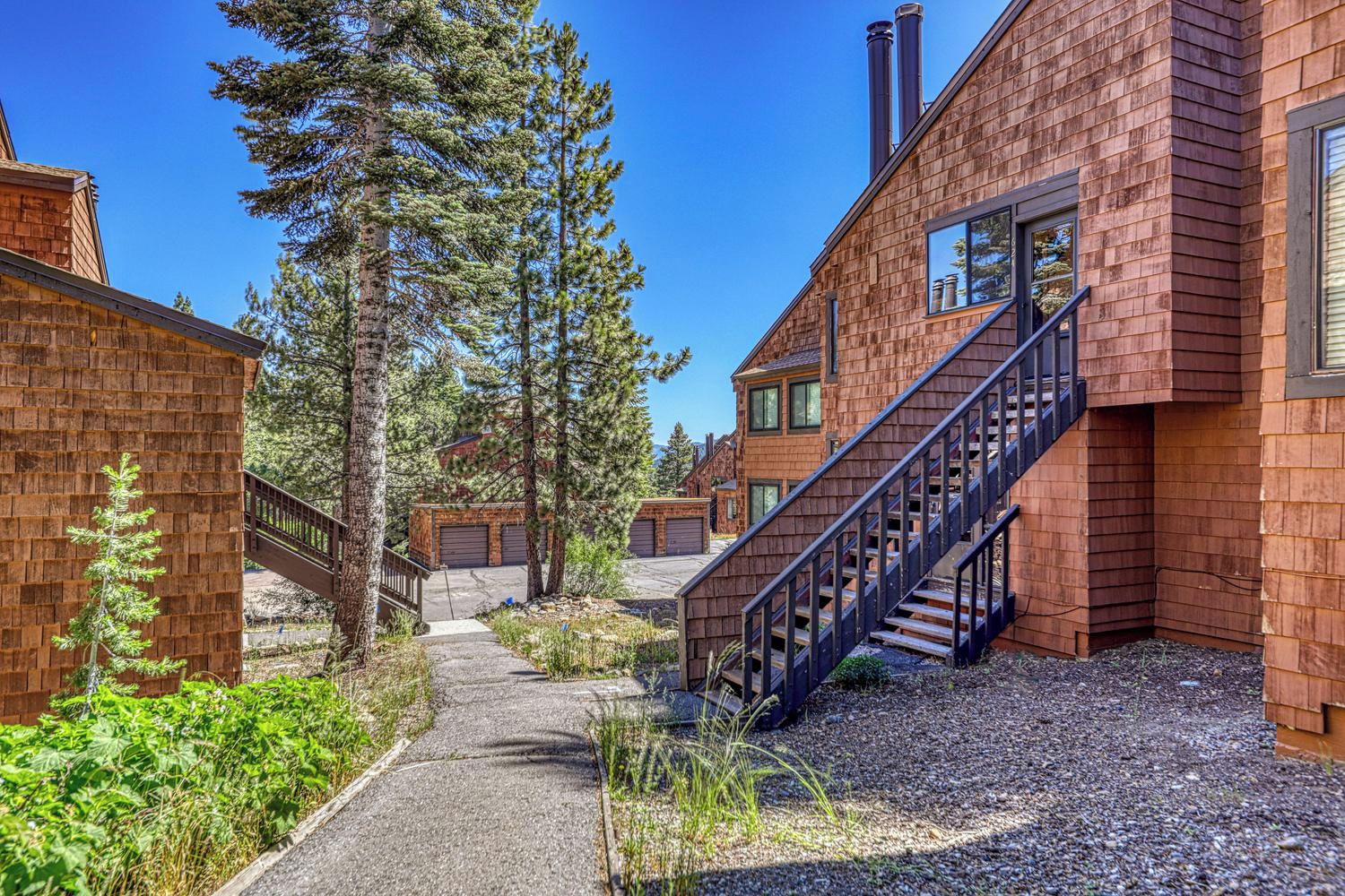 A residential building with a central staircase, a pathway, and a surrounding natural environment.