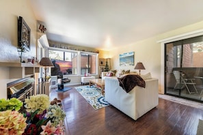 A modern living room with a white sofa, a flat-screen TV, and a fireplace. - Cozy 1BR Tahoe Donner condo with fireplace, WiFi, balcony, and resort access. (Truckee)