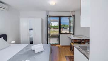 Habitación de hotel con cama, escritorio, kitchenette pequeño y balcón con vista.