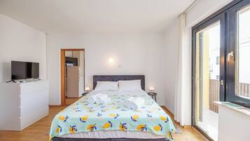 Una habitación de hotel con una cama, televisión, escritorio y ventana.