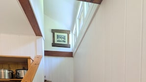 Eine Holztreppe mit weiß verkleideten Wänden und einem Bild in einem Rahmen darüber.