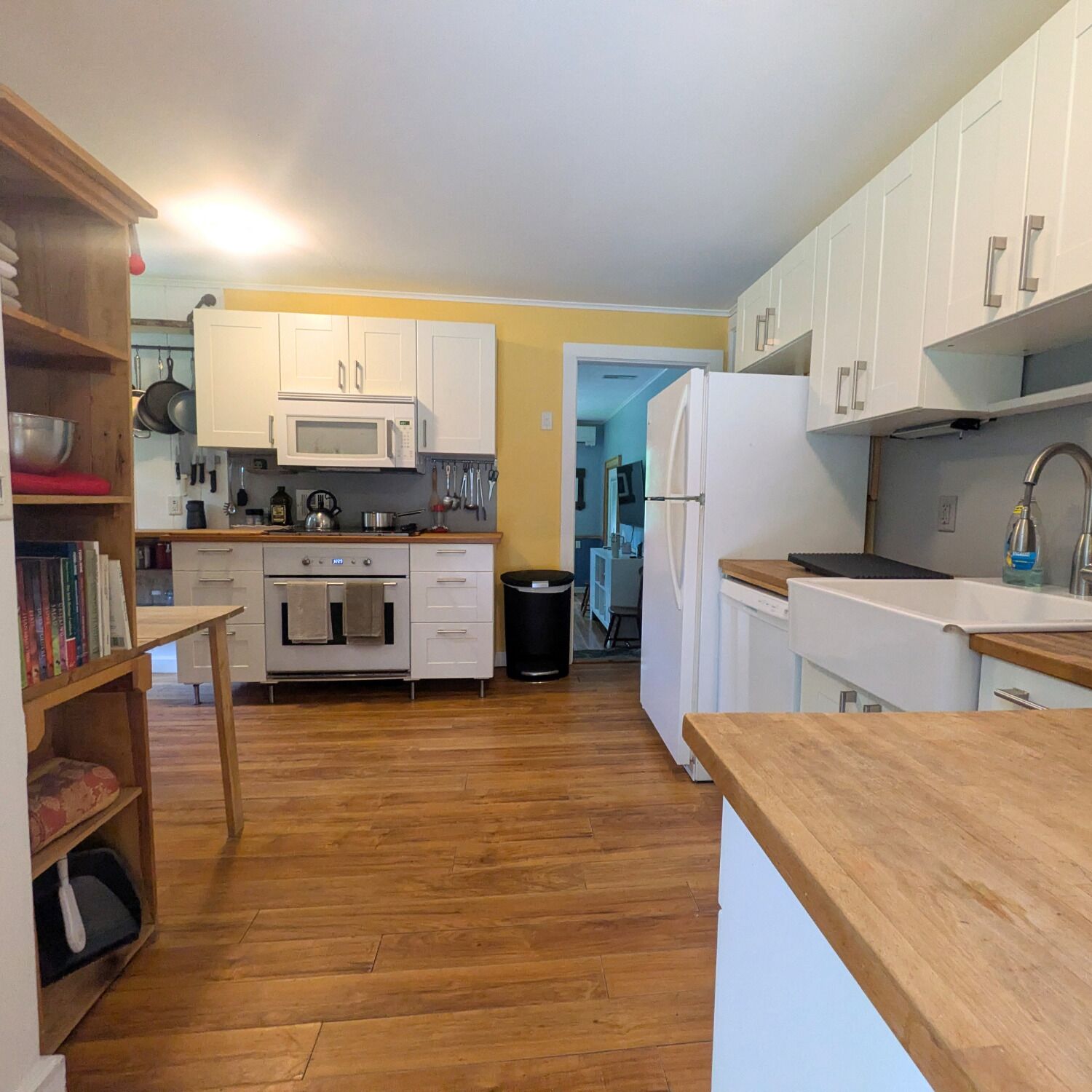 A kitchen with white cabinets, a microwave, an oven, and a refrigerator.