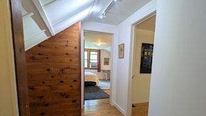Eine hölzerne Treppe führt zu einem Schlafzimmer mit Bett und Fenster.