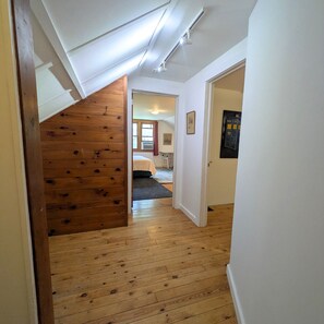 Una escalera de madera que lleva a un dormitorio con cama y ventana.