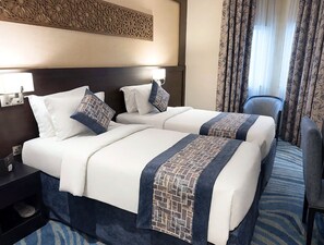 A hotel room with two beds, a nightstand, a chair, and a decorative wall panel. - Elaf Al Sagryah (Makkah)