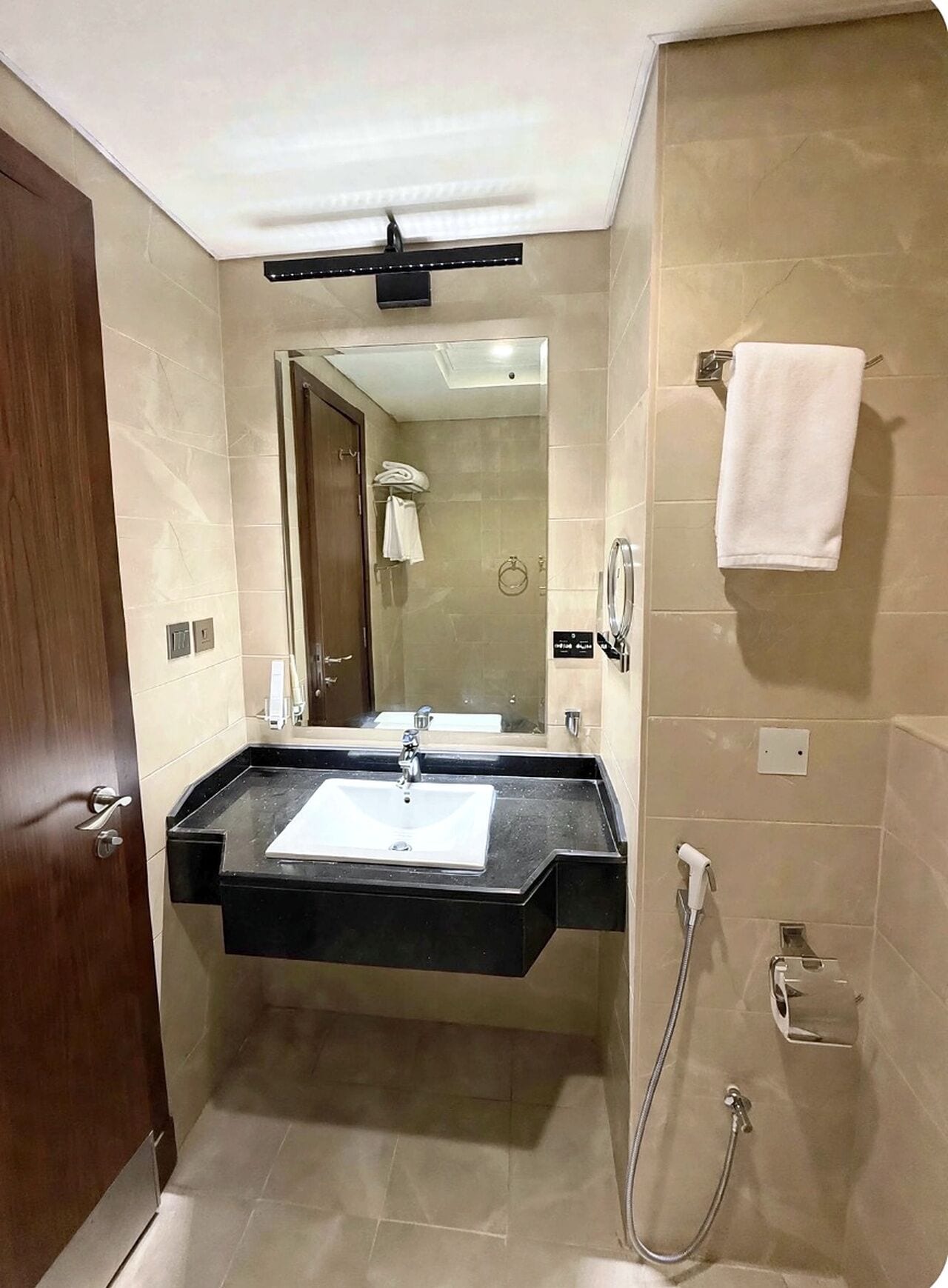 Une salle de bain moderne avec un lavabo sur pied, un miroir, un porte-serviettes et un espace douche.