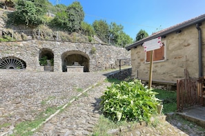 A stone building with a signpost indicating directions to local attractions. - Holiday home 'Agnese' with lake view, private terrace and Wi-Fi (Pradello)