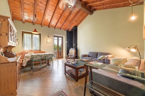 A cozy living area with a wooden ceiling, a dining table with chairs, a sofa, and a coffee table. - Holiday home 'Agnese' with lake view, private terrace and Wi-Fi (Pradello)