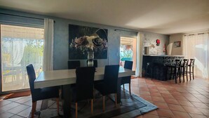 A dining area with a table and chairs, a vase with flowers, and a cityscape painting on the wall.