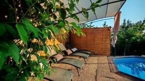 An outdoor seating area with lounge chairs and a pool.