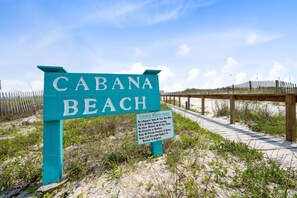 Schild für Cabana Beach, mit einer hölzernen Promenade, die zum Strand führt.