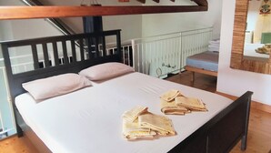 Ein Schlafzimmer mit einem hölzernen Bett, weißen Leinen und Handtüchern auf dem Bett.