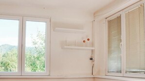 A room with a wooden table and bench, a window with blinds, and a shelf with items. - Vikendica Boracko jezero - Zen Lake (Konjic)