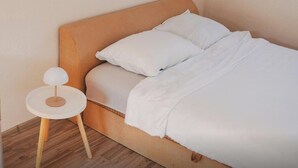 A single bed with a wooden headboard, white bedding, and a small round side table with a lamp. - Vikendica Boracko jezero - Zen Lake (Konjic)