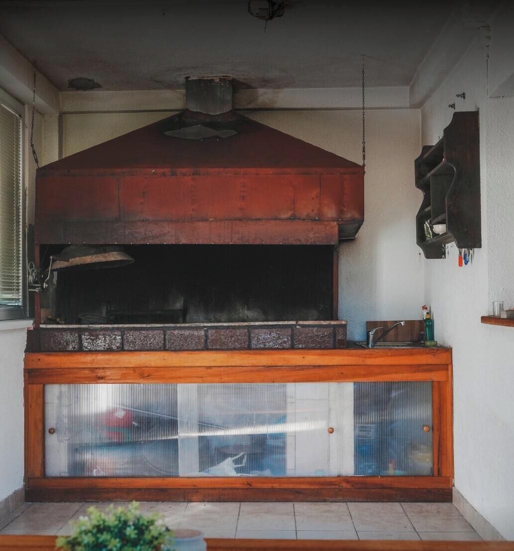 A kitchen with a large built-in oven, a wooden countertop, and a window with blinds.
