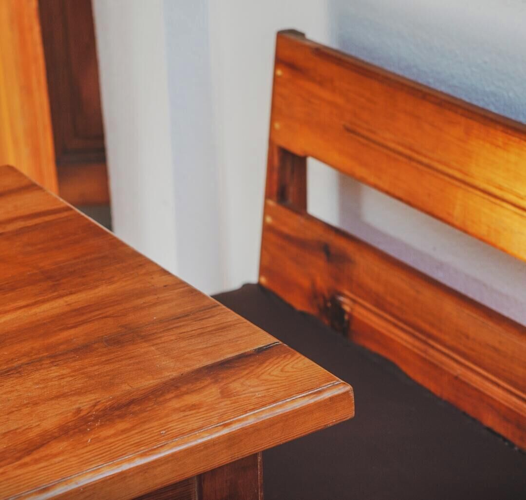 Una mesa de madera con el borde visible y un cabecero de madera al fondo.