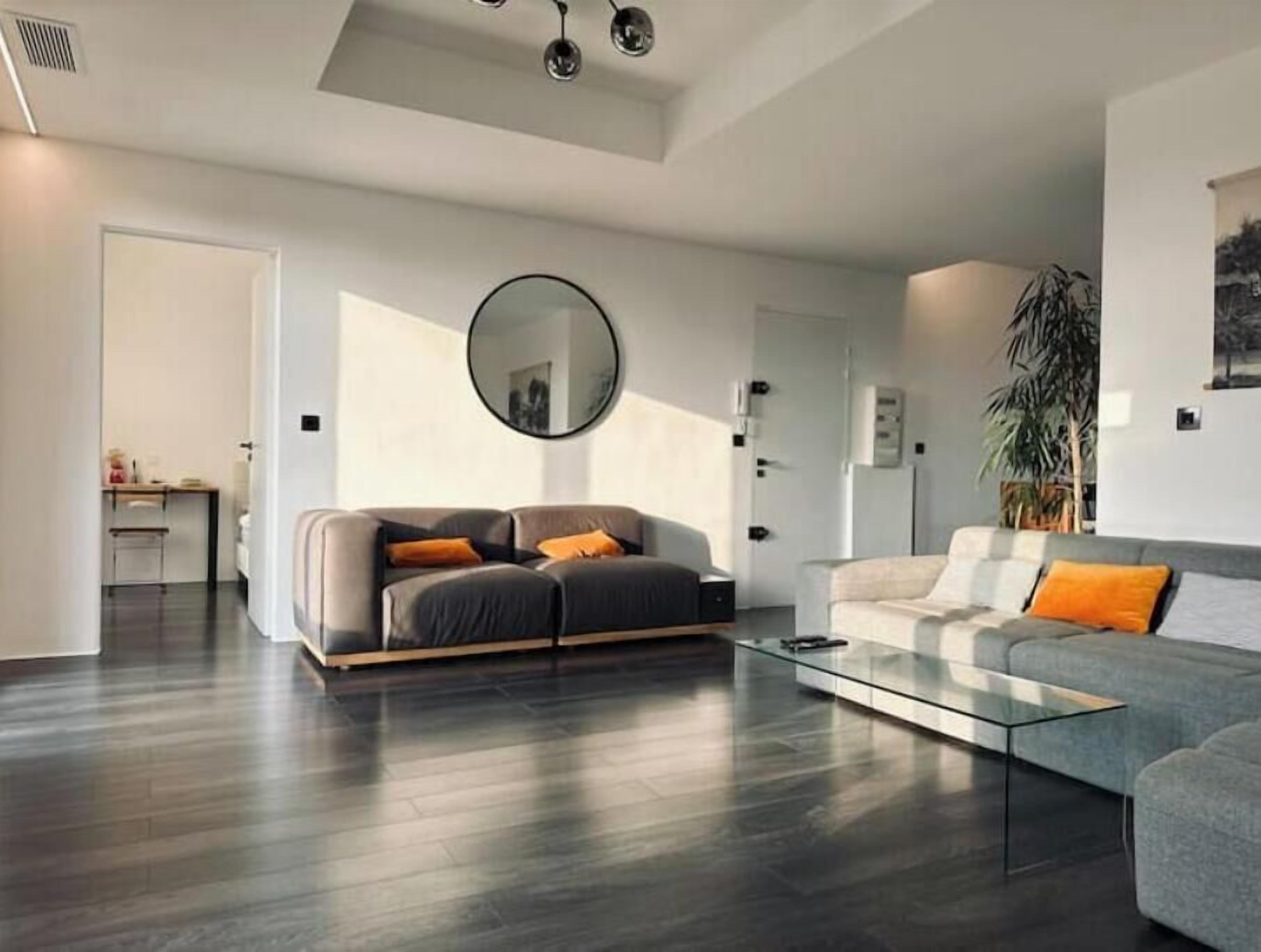 A modern living room with two sofas, a coffee table, and a large mirror.