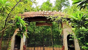 A rustic wooden archway with a metal gate, surrounded by lush greenery.