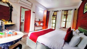 A hotel room with a bed, a bedside table, a mirror, and a window with curtains.